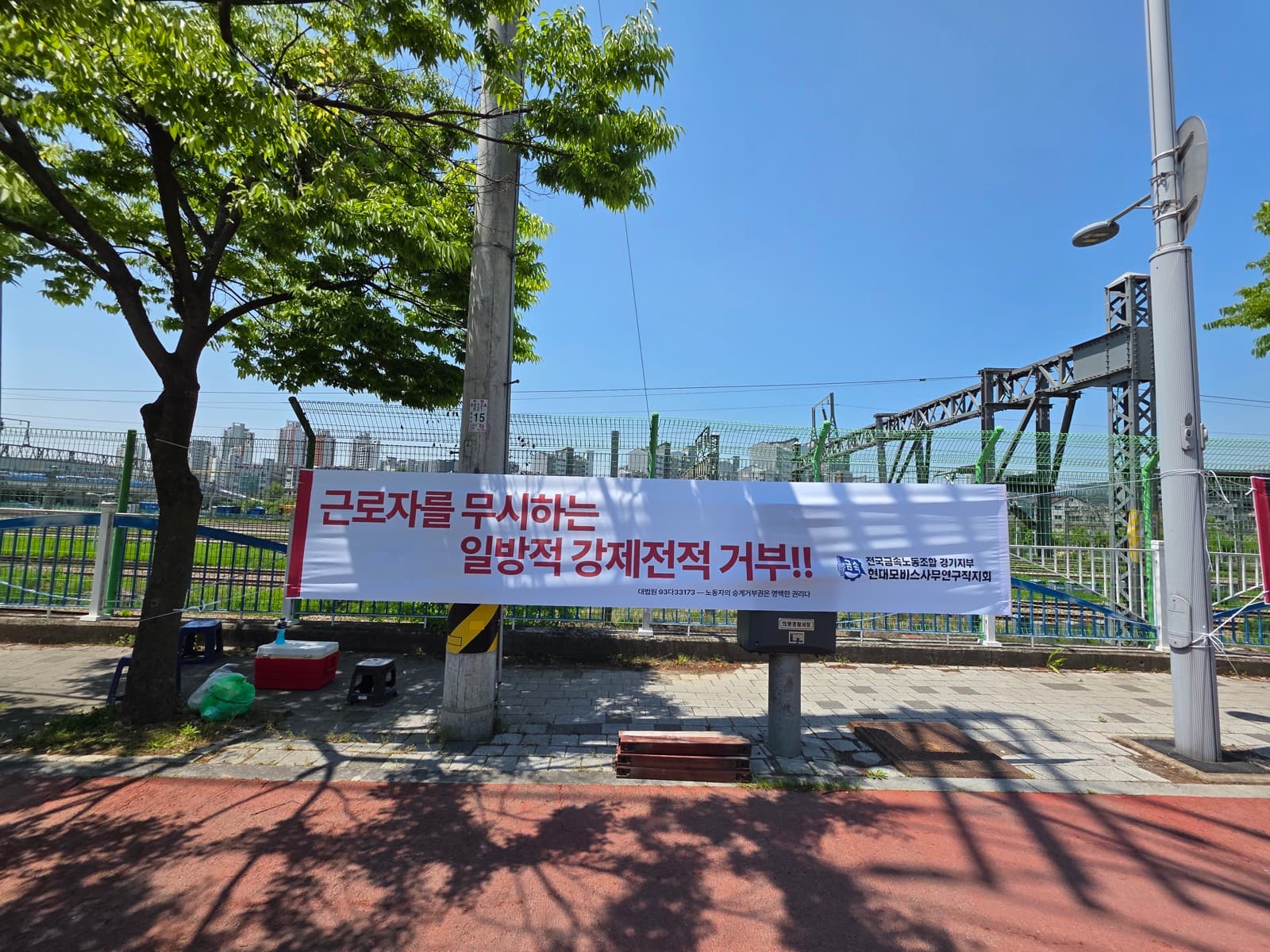 현수막: 근로자를 무시하는 일방적 강제전적 거부!!