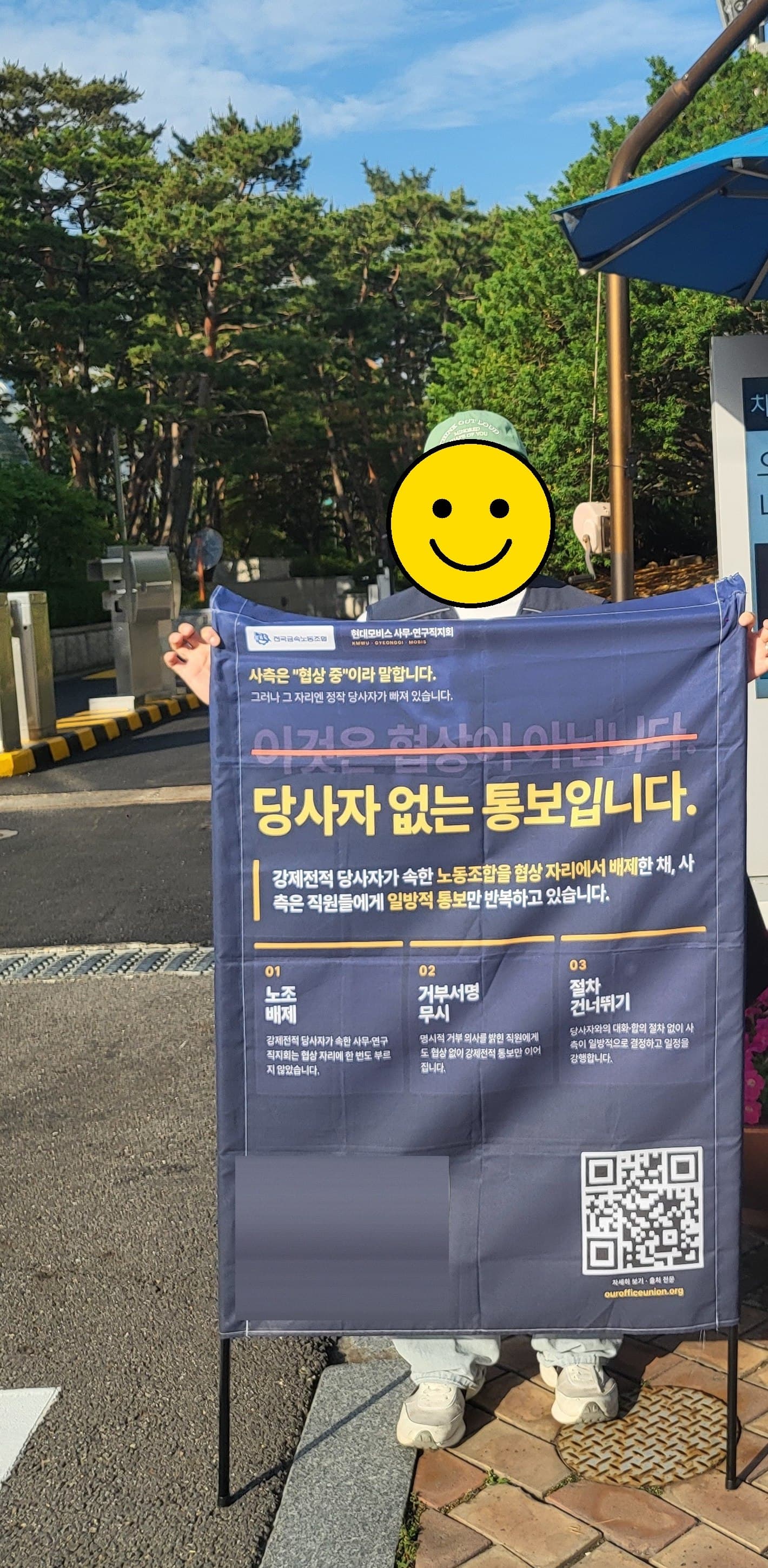 서울 양재동 현대자동차그룹 본사 앞에서 “당사자 없는 통보입니다” 폼보드를 들고 선 현대모비스 사무연구직지회 조합원의 모습 (얼굴은 식별되지 않도록 처리)