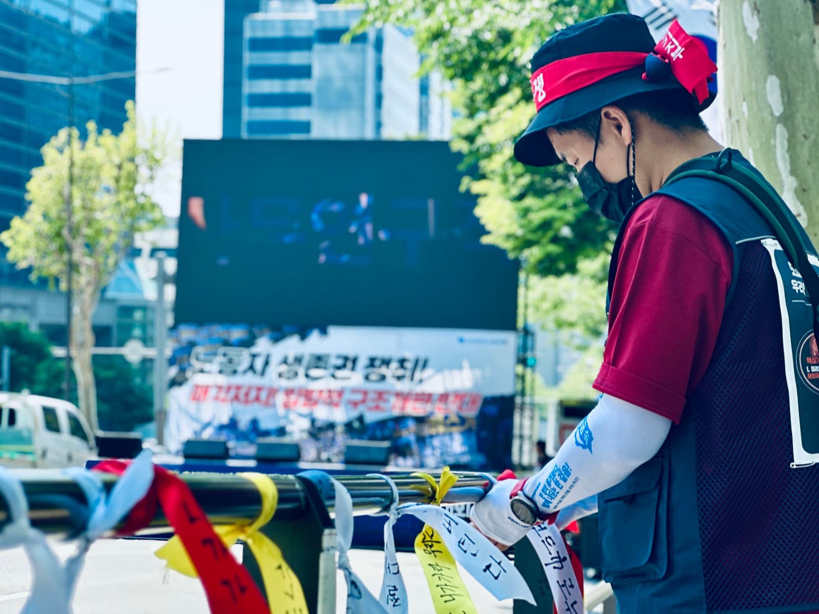 「투쟁」 머리띠를 쓰고 사무연구직지회 팔토시를 착용한 조합원이 무대 앞 바리케이드에 리본을 매는 모습