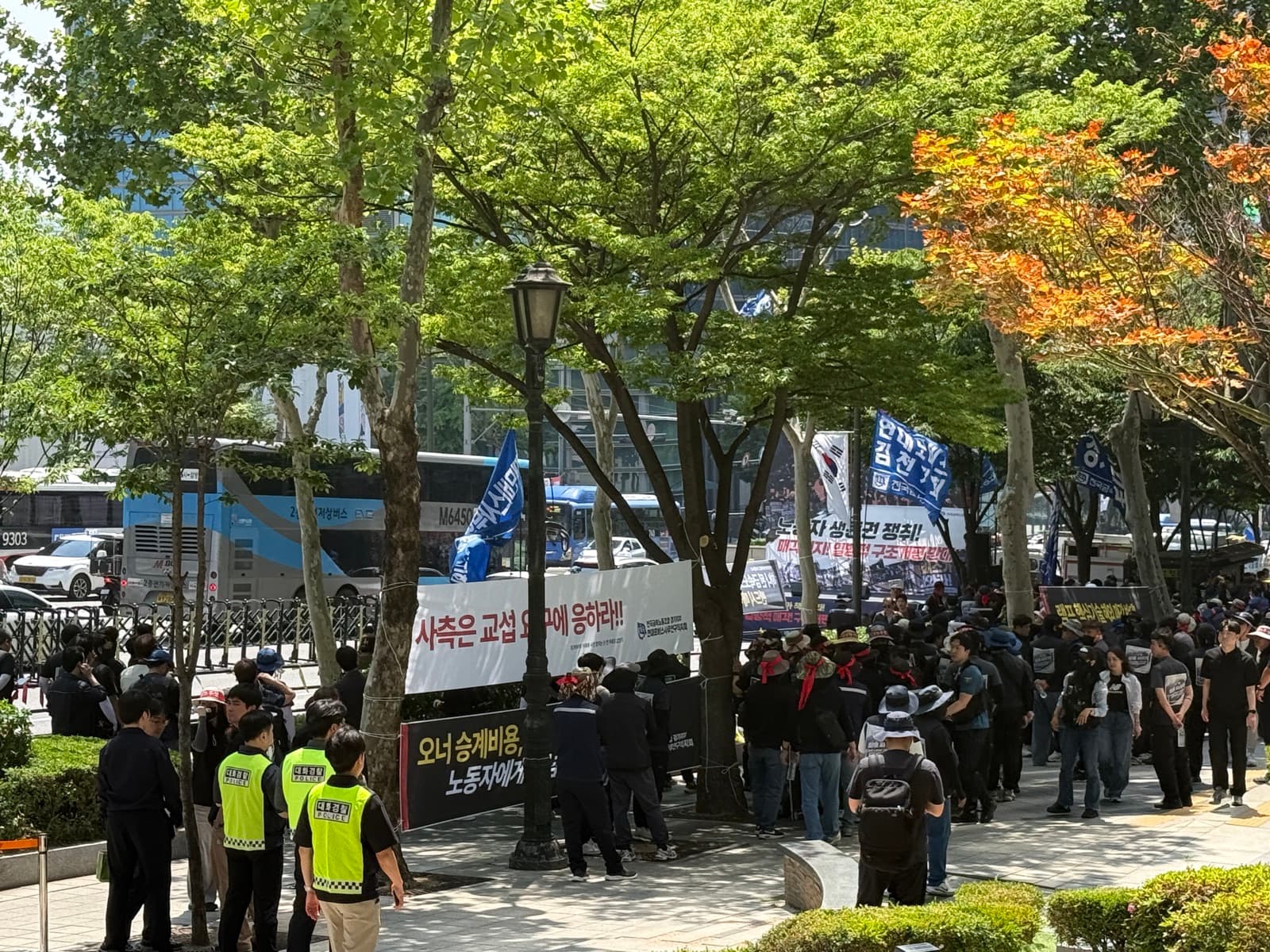 「사측은 교섭 요구에 응하라」 현수막과 집회 대오, 경찰 안내
