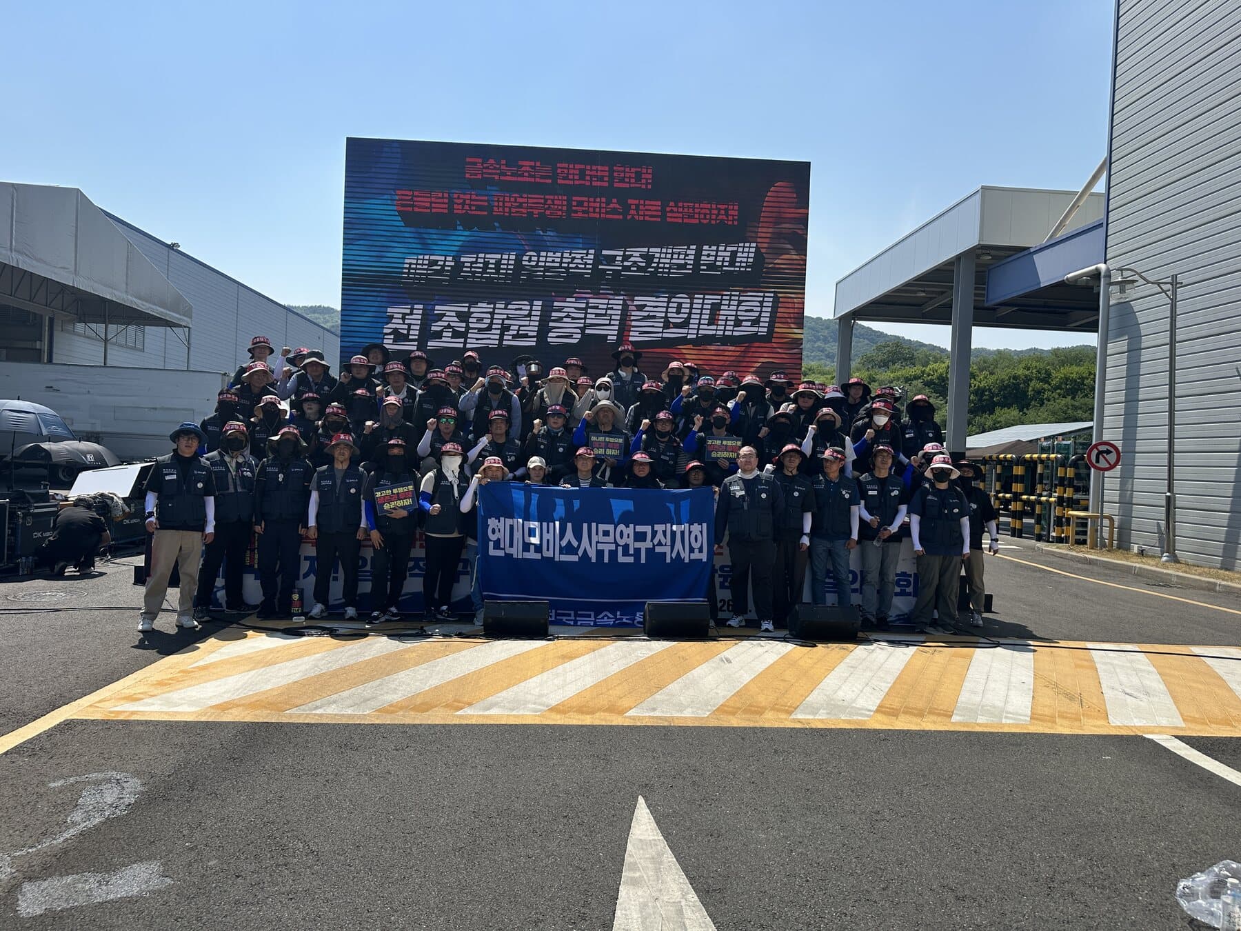 결의대회 무대 앞 — '매각 저지! 일방적 구조개편 반대! 전 조합원 총력 결의대회' 대형 화면 아래 모인 사무연구직지회 조합원들
